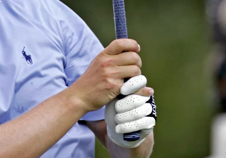 A man holding a golf club with an interlocking grip